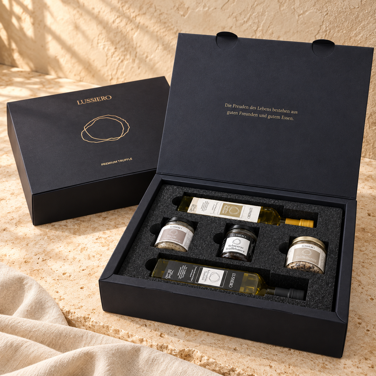 Geöffnete Lussiero Geschenkbox mit zwei Trüffelölen, zwei Trüffelsaucen und Trüffelbutter auf hellem Stein
